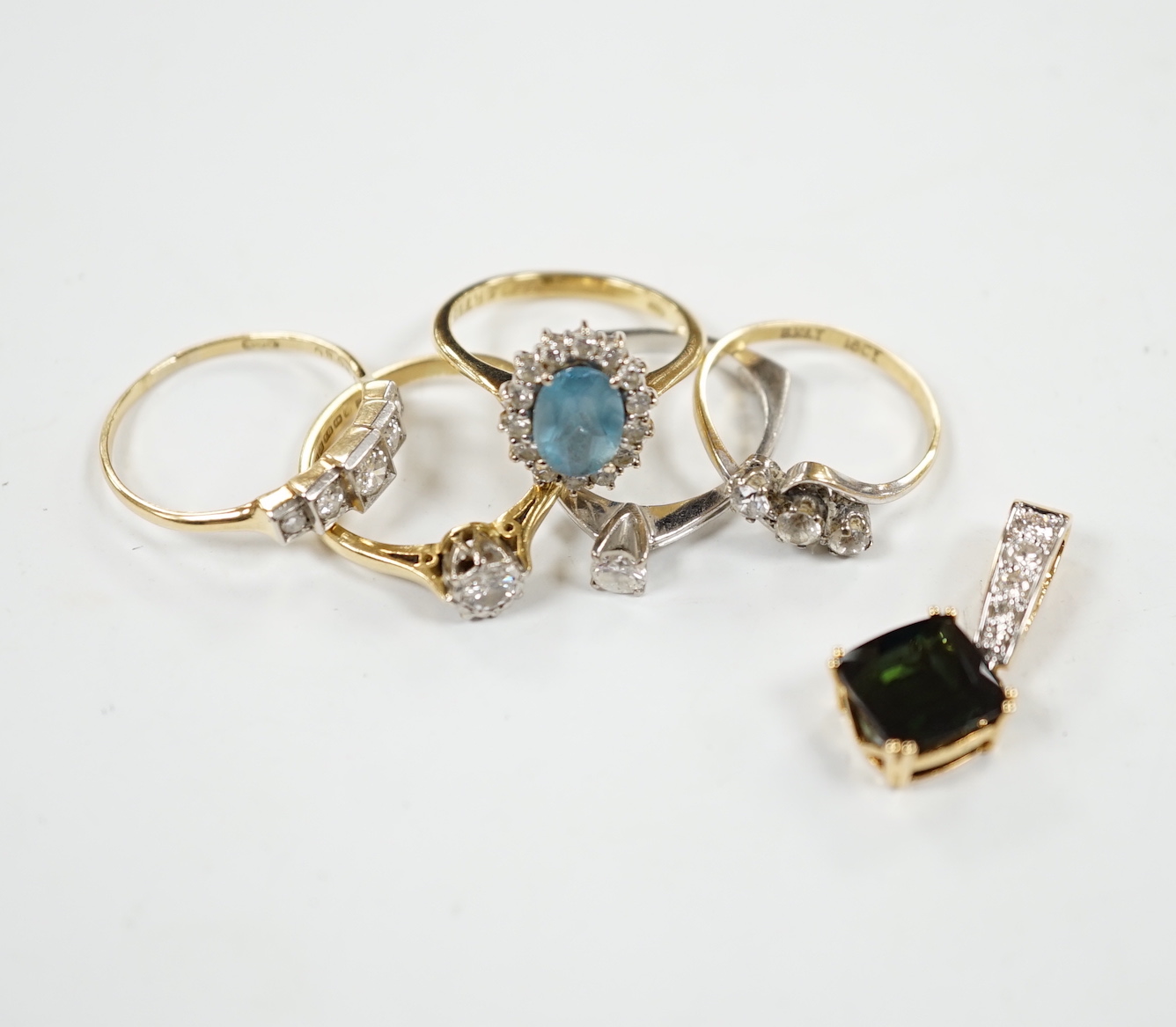 Five assorted modern 18ct and gem set rings, including two solitaire diamond rings and a graduated five stone diamond ring, together with a modern 18ct, green stone and diamond cluster set pendant, gross weight 16 grams.
